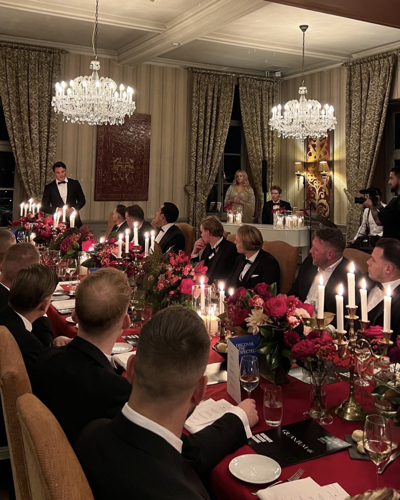 Diner in black tie met een spreker aan tafel en Quantum-boekjes op tafel